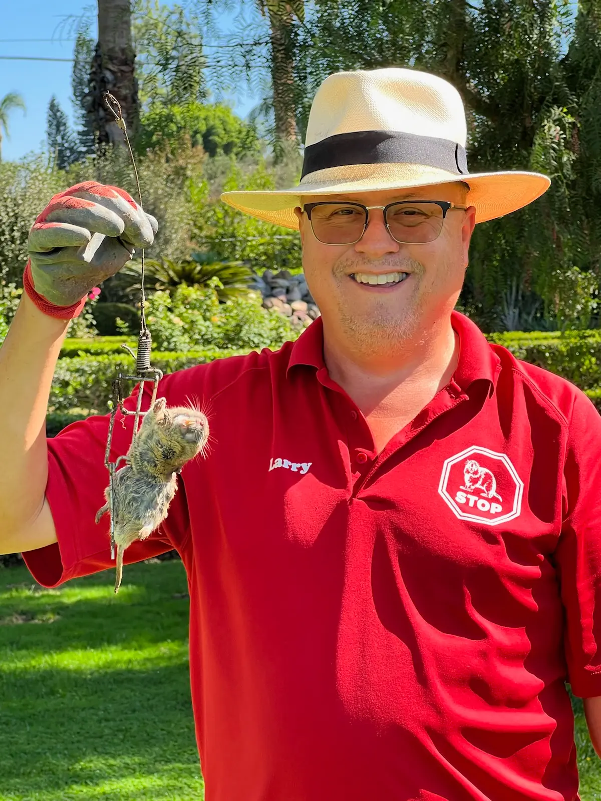 Gopher Stop technician in a red polo holding up a gopher caught in a professional kill trap
