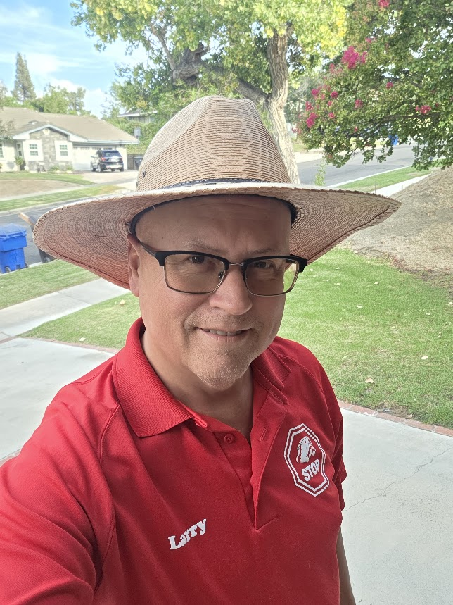 Gopher Stop technician Larry in a straw hat and red Gopher Stop shirt on a sunny Perris street, ready to clear the yard before replanting