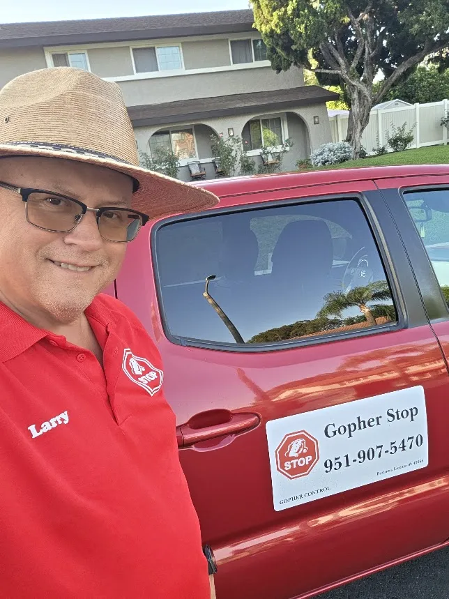 Gopher Stop technician Larry stands beside his red service truck in a Loma Linda neighborhood before clearing a yard, reading the gopher runs and removing the whole colony with no poison.